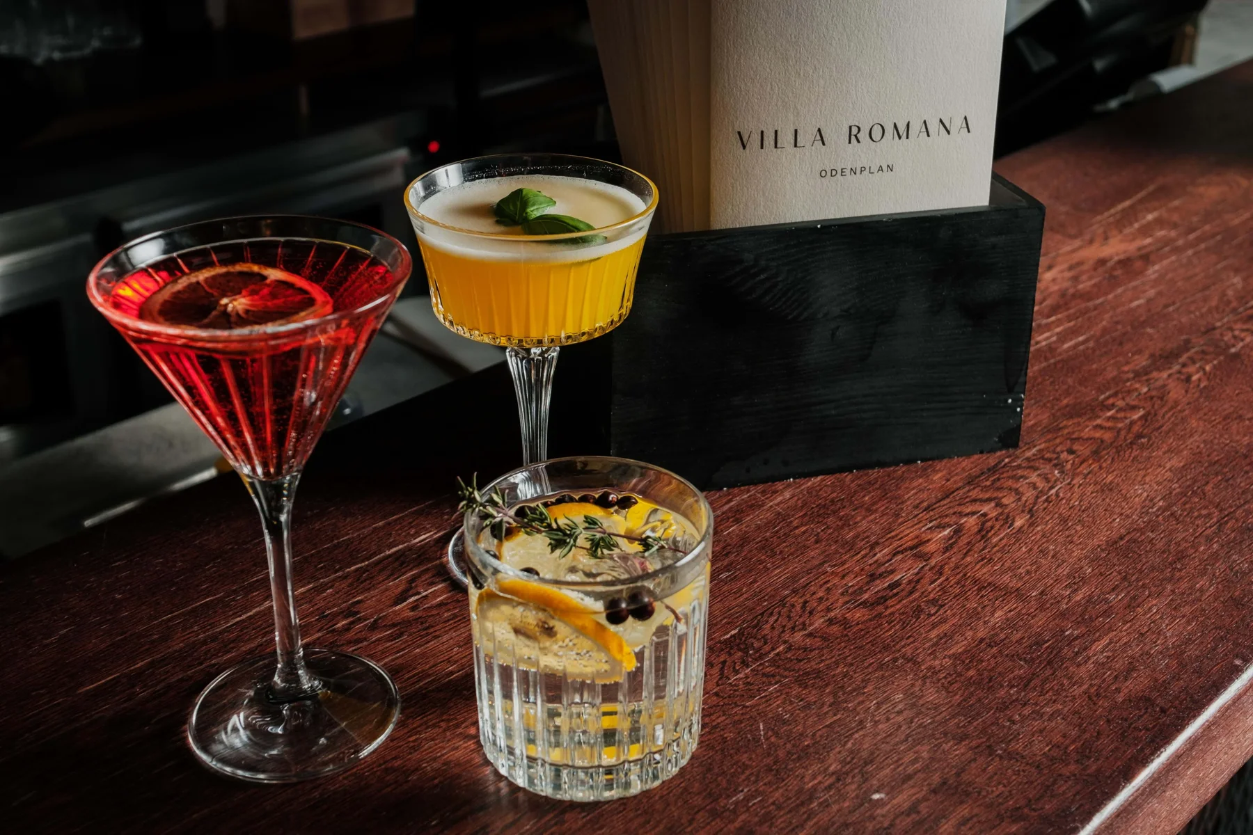 Tre drinkar och Villa Romanas meny på bardisken