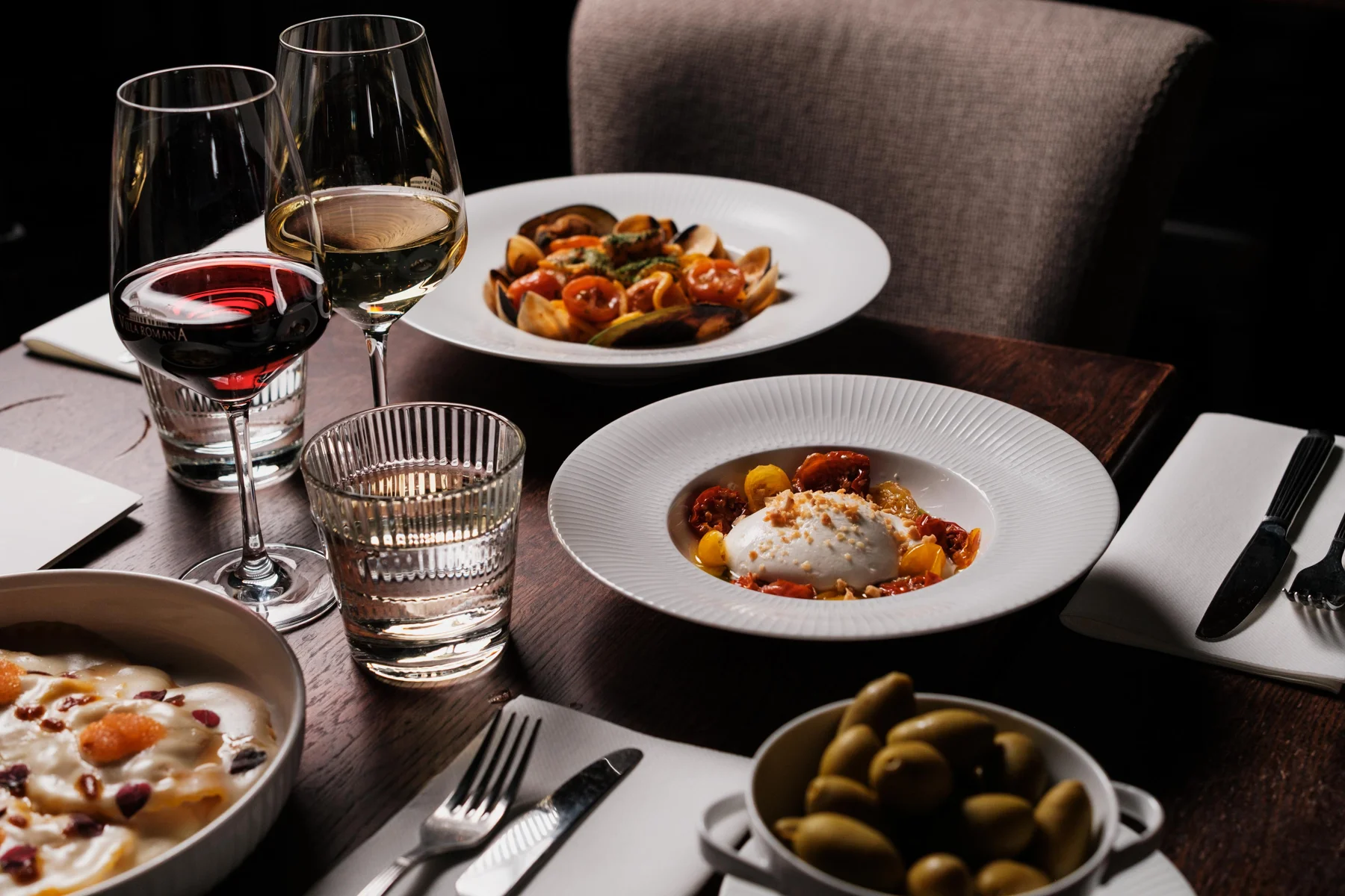 Italienska pastarätter och vin på ett dukat bord hos Villa Romana